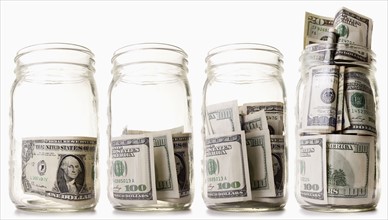 Glass jars filled with dollar bills. 
Photo : Mike Kemp