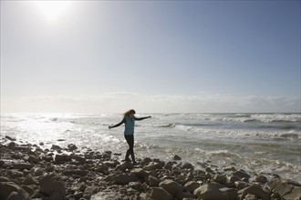 France, Pas-de-Calais, Escalles, Young woman strolling on rocky beach. 
Photo: Jan Scherders