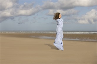France, Pas-de-Calais, Escalles, Young woman strolling on empty beach. 
Photo : Jan Scherders