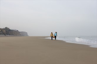 France, Pas-de-Calais, Escalles, Two women strolling on empty beach. 
Photo: Jan Scherders