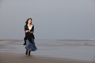 France, Pas-de-Calais, Escalles, Young woman strolling on empty beach. 
Photo : Jan Scherders