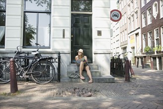 Holland, Amsterdam, Female tourist with map sitting on steps. 
Photo : Jan Scherders