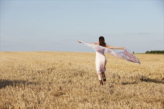 France, Picardie, Albert, Young woman running through stubble with shawl. 
Photo: Jan Scherders