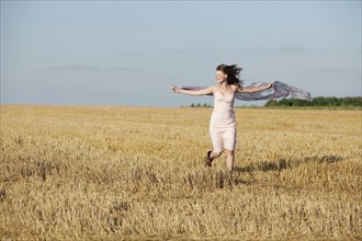 France, Picardie, Albert, Young woman running through stubble with shawl. 
Photo : Jan Scherders