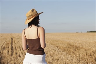 France, Picardie, Albert, Young woman in straw hat looking at country landscape. 
Photo : Jan