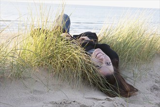 Netherlands, Zeeland, Haamstede, Woman lying on sand dune. 
Photo: Jan Scherders