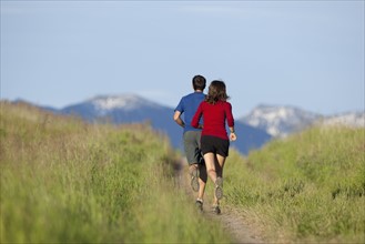 USA, Montana, Kalispell, Couple jogging in mountainside. 
Photo: Noah Clayton