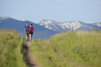 USA, Montana, Kalispell, Couple jogging in mountainside. 
Photo: Noah Clayton