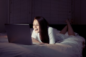 Woman using laptop in bed. 
Photo : King Lawrence