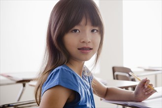 Portrait of schoolgirl holding pencil. 
Photo: Rob Lewine