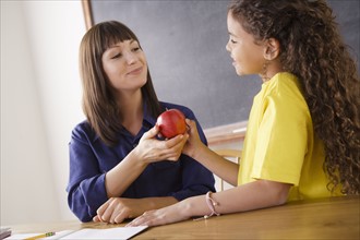 Teacher receiving apple from schoolgirl. 
Photo : Rob Lewine