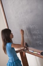 Schoolgirl writing on blackboard. 
Photo : Rob Lewine