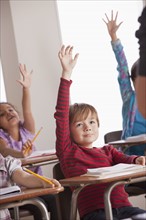 Pupils in classroom raising hands. 
Photo : Rob Lewine