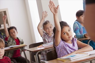 Pupils in classroom raising hands. 
Photo: Rob Lewine