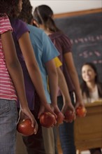 pupils standing in row (10-11, 12-13) holding apple with teacher in background. 
Photo: Rob Lewine