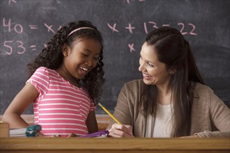 Schoolgirl (10-11) and teacher with blackboard in background. 
Photo : Rob Lewine