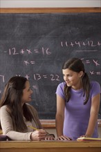 Schoolgirl (12-13) and teacher face to face with blackboard in background. 
Photo: Rob Lewine