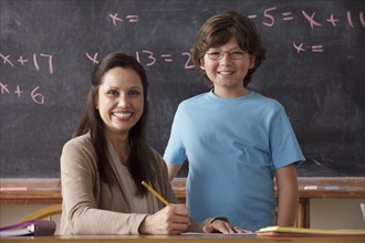 Portrait of schoolboy (10-11) and teacher with blackboard in background. 
Photo: Rob Lewine