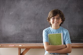 Portrait of schoolboy (10-11) in front of blackboard. 
Photo : Rob Lewine