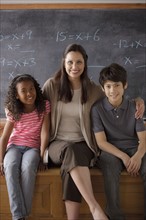 Portrait of teacher in classroom with schoolboy (10-11) and schoolgirl (12-13). 
Photo: Rob Lewine