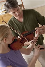 Teacher showing to teenage girl (14-15) how to play violin. 
Photo : Rob Lewine