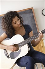 Teenage girl (16-17) playing guitar. 
Photo : Rob Lewine