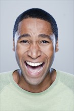 Portrait of laughing young man, studio shot. 
Photo : Rob Lewine