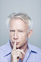 Portrait of senior man with finger on lips, studio shot. 
Photo: Rob Lewine