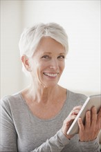 Smiling senior woman using digital tablet. 
Photo : Rob Lewine