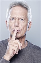 Portrait of senior man with finger on his lips, studio shot. 
Photo: Rob Lewine