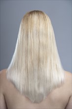Rear view of woman with blonde hair, studio shot. 
Photo : Mark de Leeuw