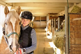 Portrait of teenage girl (16-17) with horse in stable. 
Photo: Elena Elisseeva