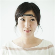Portrait of young woman with word 'enlightenment' on forehead, studio shot. 
Photo : Jessica