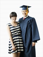 Portrait of young couple, man in graduation gown. 
Photo: Jessica Peterson