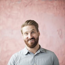 Portrait of laughing young man against pin background. 
Photo : Jessica Peterson
