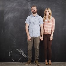 Young couple with blackboard in background, studio shot. 
Photo: Jessica Peterson
