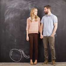 Young couple with blackboard in background, studio shot. 
Photo : Jessica Peterson