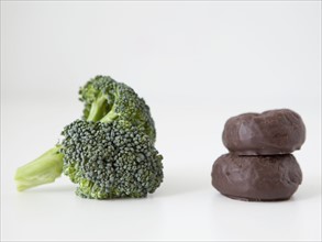 Broccoli and chocolate cookies on white background, studio shot. 
Photo : Jessica Peterson