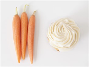Carrots and muffin on white background, studio shot. 
Photo : Jessica Peterson