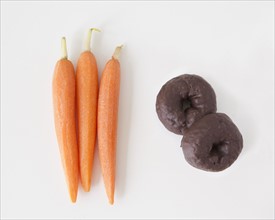 Carrots and chocolate cookies on white background, studio shot. 
Photo : Jessica Peterson