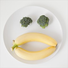 Fruit and vegetable face on plate, studio shot. 
Photo: Jessica Peterson