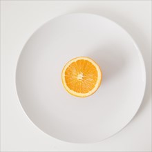 Half of orange on plate, studio shot. 
Photo: Jessica Peterson