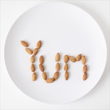 Word 'Yum' made out of almonds on plate, studio shot. 
Photo: Jessica Peterson