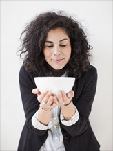 Studio shot of young woman holding white bowl. 
Photo : Jessica Peterson
