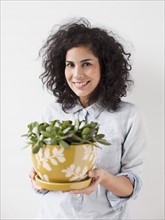 Beautiful young woman holding pot plant. 
Photo : Jessica Peterson