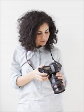 Beautiful young woman holding professional camera. 
Photo : Jessica Peterson