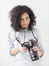 Portrait of beautiful young woman holding professional camera. 
Photo : Jessica Peterson