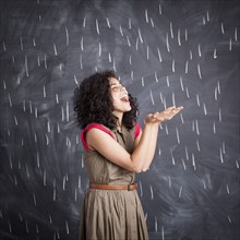 Young teacher posing against blackboard with V marks imitating rain. 
Photo : Jessica Peterson