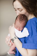 Portrait of young female nurse holding baby boy (2-5 months). 
Photo : Jessica Peterson