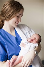 Portrait of young female nurse holding baby boy (2-5 months). 
Photo : Jessica Peterson